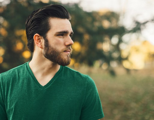 Jeune homme avec chandail vert qui regarde à l'horizon vers la droite.